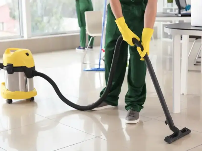 Cleaner vacuuming construction dust from floor during post-construction cleaning in Indore