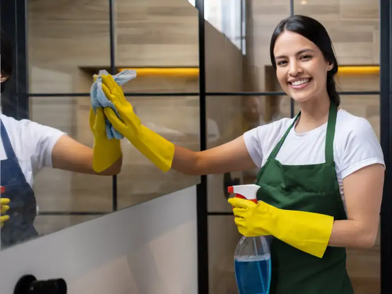 Professional cleaner cleaning a glass door in an Indore home