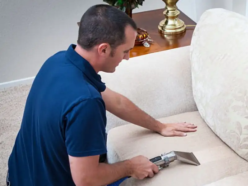 Technician shampooing a fabric sofa with extraction machine in Indore home